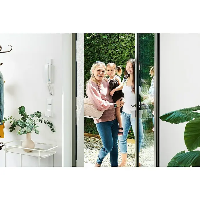 Nuki Elektrischer Türöffner Opener - Passend für: Nuki Smart Lock - Eine Familie betritt ein Haus mit einer modernen Türsprechanlage. Die Türsprechanlage ist weiß und an der Wand montiert.