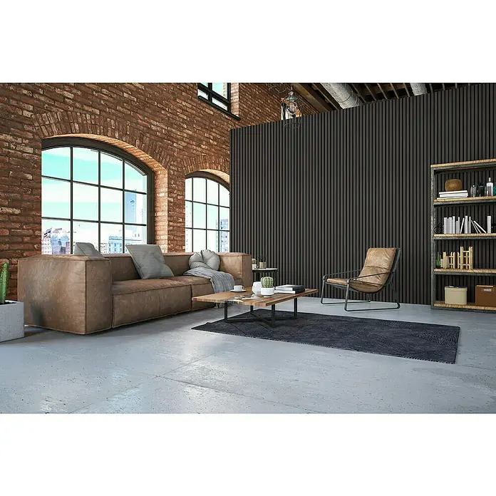 FibroTech Akustikpaneel Premium - Black Oak, 2.440 x 605 x 22 mm - Lässiges Wohnzimmer mit braunem Ledersofa, Teppich, Holztisch, Lesesessel, schwarzer Regal und großen Fenstern in einem Raum mit Ziegelwand.