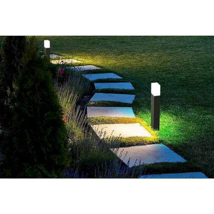 Lavida Milan Außensockelleuchte - 12 W, Farbe Gehäuse: Schwarz, Neutralweiß, 6,4 x 9,5 x 50 cm, Mit Leuchtmittel, Ohne Steckdose - Ein Gartenweg beleuchtet mit modernen, quadratischen Gartenleuchten, die ein warmes Licht auf die Steinplatten und das umgebende Grün werfen.