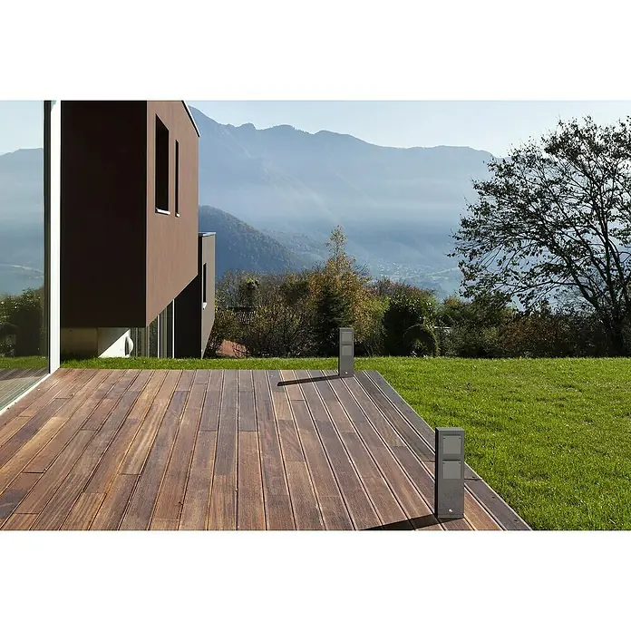 Lavida Milan Energiesäule - Anzahl Steckdosen Schuko: 2 Stk., 32 cm, Grau - Ansicht eines modernen Holzdecks mit stilvollen Pollerleuchten und einem malerischen Blick auf die Berge.