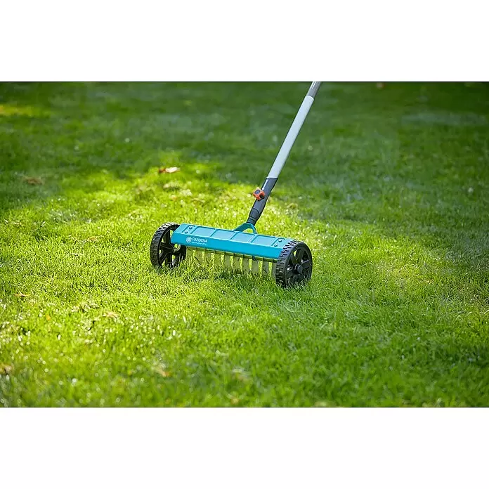 Gardena Combisystem Vertikutierboy - Arbeitsbreite: 32 cm, Geeignet für: Moos- und Rasenfilzentfernung - Ein blauer GARDENA Vertikutier-Boy mit schwarzen Rädern steht auf Rasen.