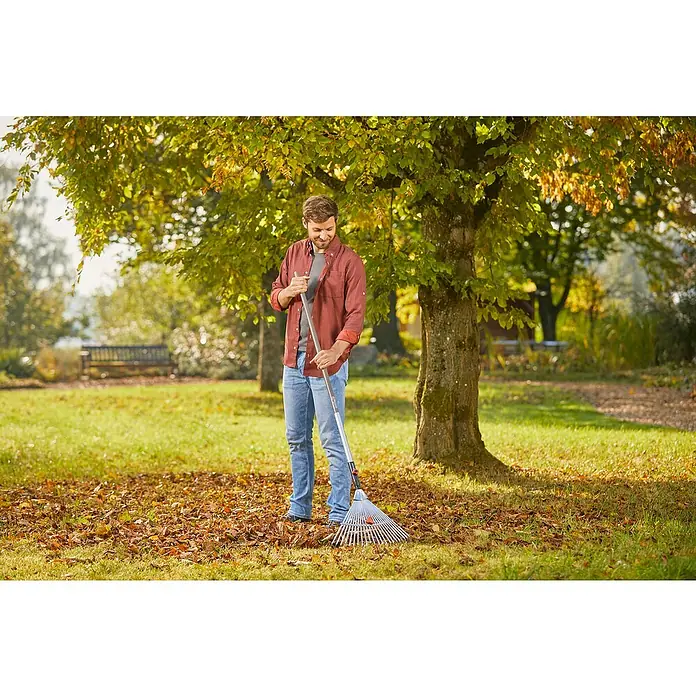 Gardena Combisystem Verstellbesen - Arbeitsbreite: 30 cm - 50 cm, Aluminium - Ein Mann harkt Laub mit einem GARDENA Rechen im Garten. Der verstellbare Rechen von GARDENA ist ideal für die Gartenarbeit im Herbst.