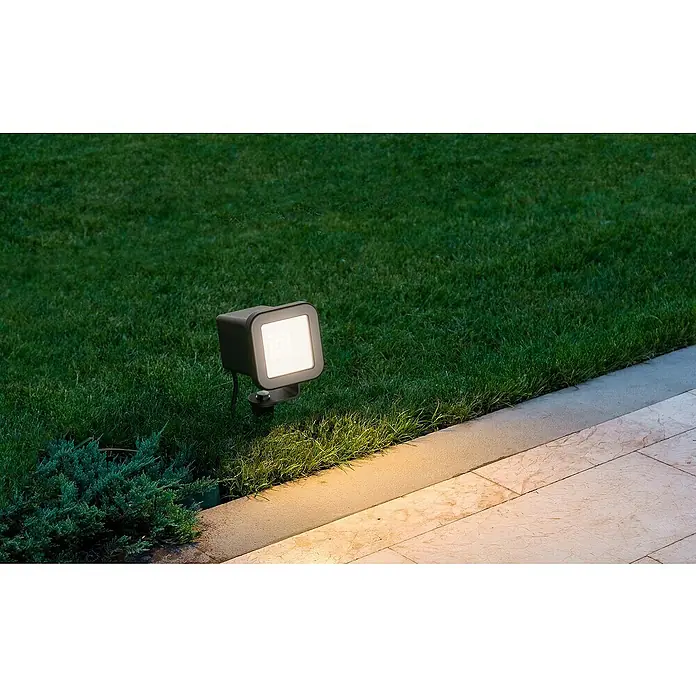 Lavida Milan LED-Strahler - 8 W, 1.300 lm, 4.000 K, L x B x H: 30,8 x 13,6 x 8,8 cm, IP65, Eckig - Eine quadratische Gartenleuchte in Schwarz erhellt einen gepflegten Rasen und einen Steinweg, für stimmungsvolle Akzente im Außenbereich.