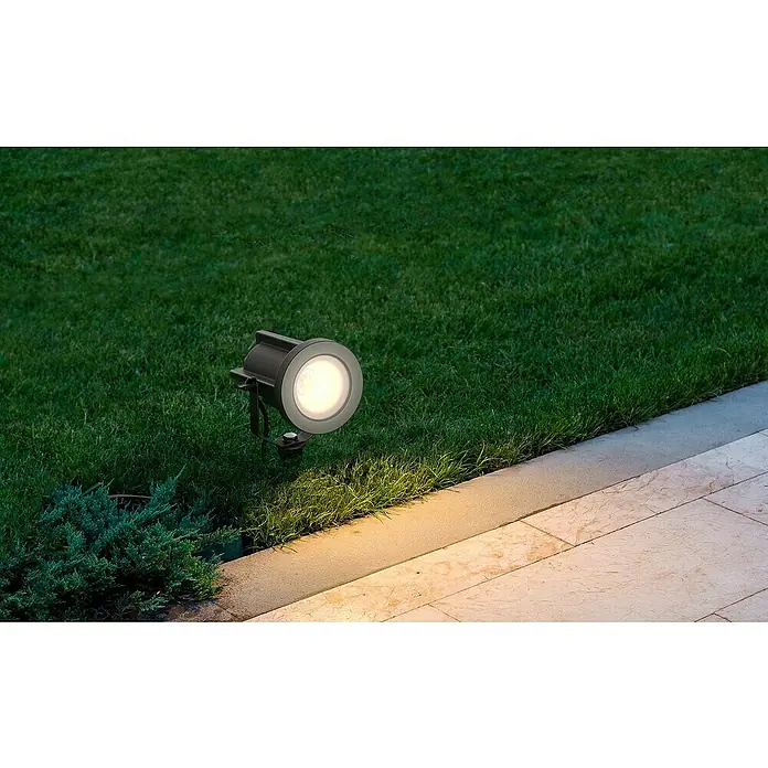Lavida Milan LED-Strahler - 8 W, 1.200 lm, 4.000 K, L x B x H: 31,6 x 15,5 x 11,5 cm, IP65, Rund - Nahaufnahme einer Außenleuchte, die Rasen und einen Steinplattenweg beleuchtet. Die Lampe ist schwarz mit einer runden, leuchtenden Mitte.