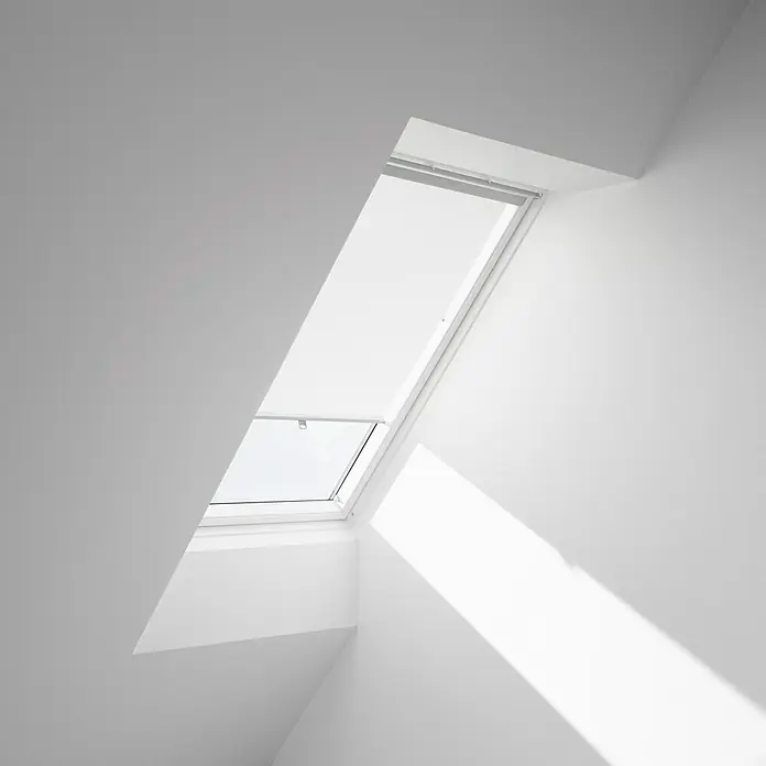 Velux Dachfensterrollo Haltekrallen RHL MK00 1028 - Farbe: Weiß - 1028, Farbe Schiene: Aluminium, Manuell - Ein Dachfenster in einem weißen Raum, das natürliches Licht hereinlässt und die Architektur betont.