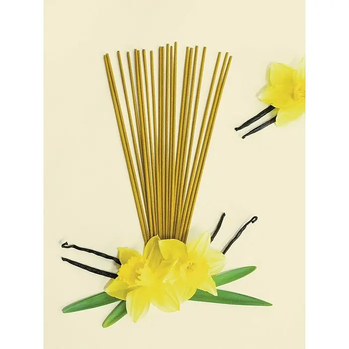 Ceras Roura Vaso con vela - Ø x Al: 7 x 8,5 cm, Vainilla - Primer plano de inciensos de vainilla con flores de narciso amarillas. Los inciensos emiten una fragancia relajante.