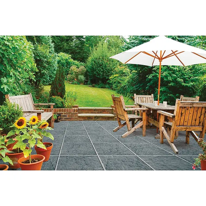 Terrassenplatte Rustica - 40 x 40 x 4 cm, Titanio, Beton - Außenbereich mit Terrassenplatten, Gartenmöbeln und Sonnenschirm, der eine entspannende Atmosphäre für Mahlzeiten im Freien schafft.