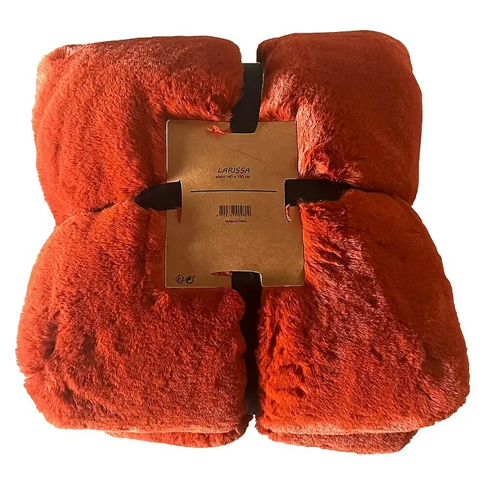 Decke LarissaPotters Clay, 180 x 140 cm, 100 % Polyester - Nahaufnahme einer gefalteten, orangefarbenen LARISSA-Decke (140 x 180 cm) mit Etikett vor schwarzem Hintergrund.