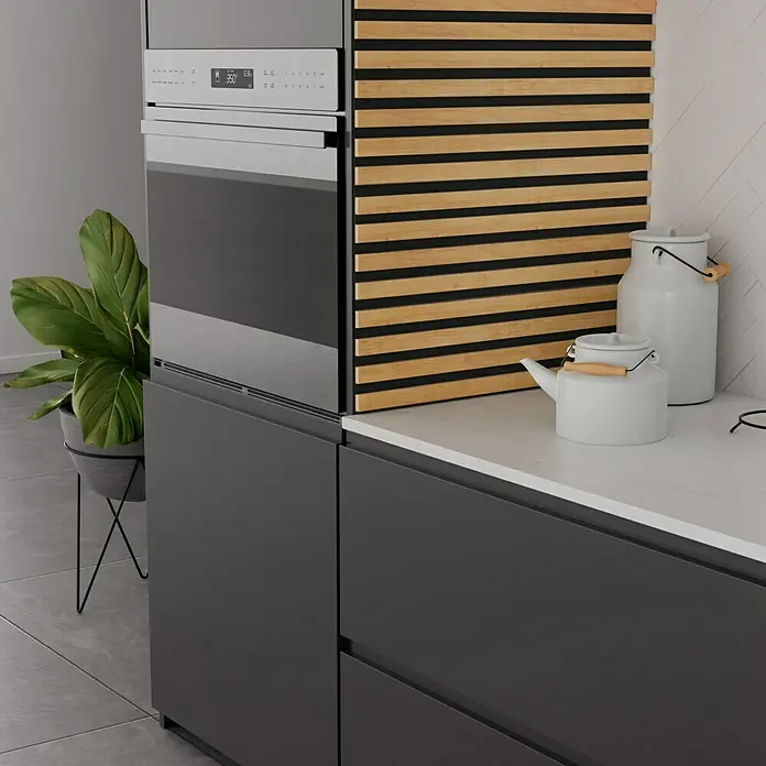 Panel acústico decorativo Premium Plus - 1,2 m x 0,6 m x 22 mm, Roble natural - Horno empotrado en una cocina moderna, con panel de madera, tetera y jarra de leche sobre una encimera blanca.