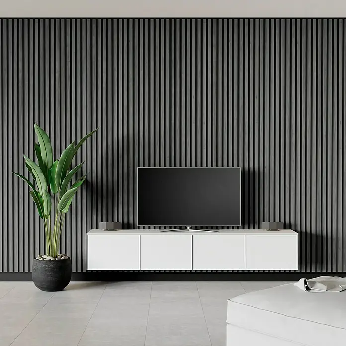 Panel acústico decorativo Premium Plus - 1,2 m x 0,6 m x 22 mm, Roble gris - Una sala de estar moderna con un mueble multimedia blanco debajo de una gran televisión, complementado por una planta de interior.