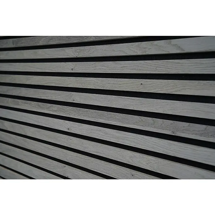 Panel acústico decorativo Premium Plus - 1,2 m x 0,6 m x 22 mm, Roble gris - Primer plano de una pared con listones de madera y fondo negro. Los listones de madera son de color gris claro y tienen una veta natural.