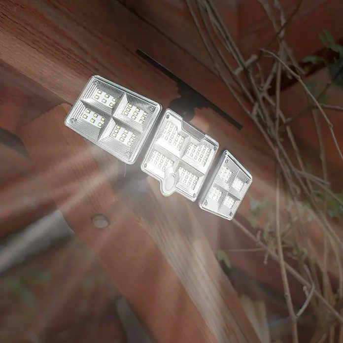 Proyector LED solar Beyong Bight X3 - Blanco frío, 1.000 lm - Primer plano de una luz LED de energía solar con tres paneles, montada sobre una superficie de madera y que brilla intensamente.