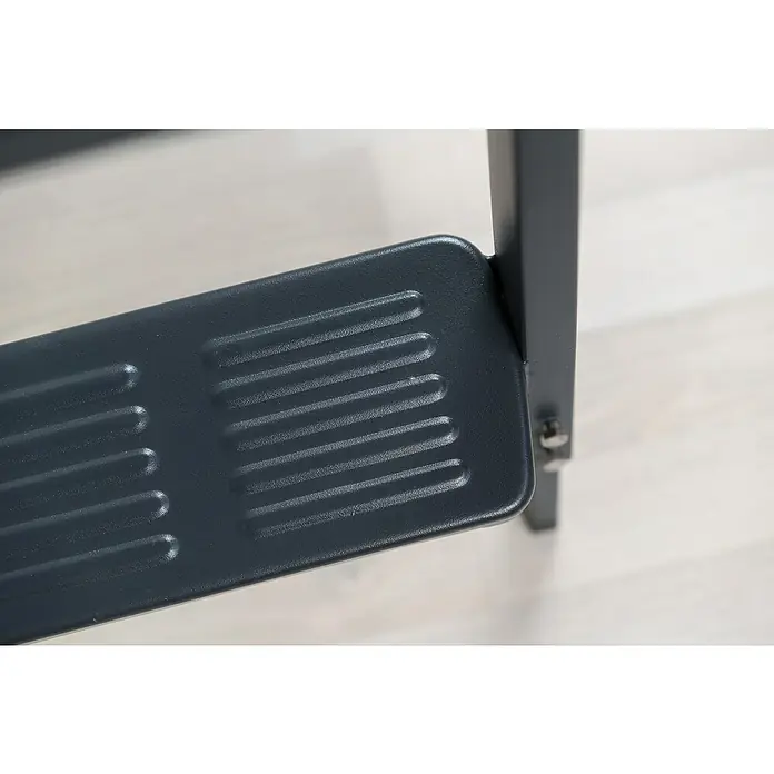 Sogem Escalera escamoteable Isoclic Pro Confort - 120 x 60 cm, Aislamiento térmico: 0,49 W/(m²K) - Primer plano de un reposapiés gris acanalado fijado a un mueble, montado sobre un marco de metal oscuro contra una superficie clara.