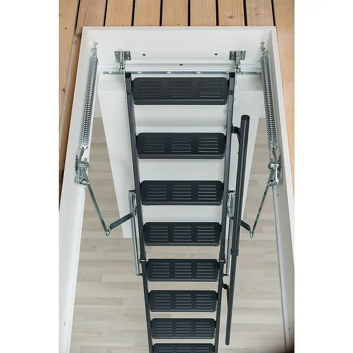 Sogem Escalera escamoteable Isoclic Pro Confort - 120 x 60 cm, Aislamiento térmico: 0,49 W/(m²K) - Una escalera de ático bajada con escalones negros y resortes de asistencia, instalada dentro de una abertura de techo blanca.