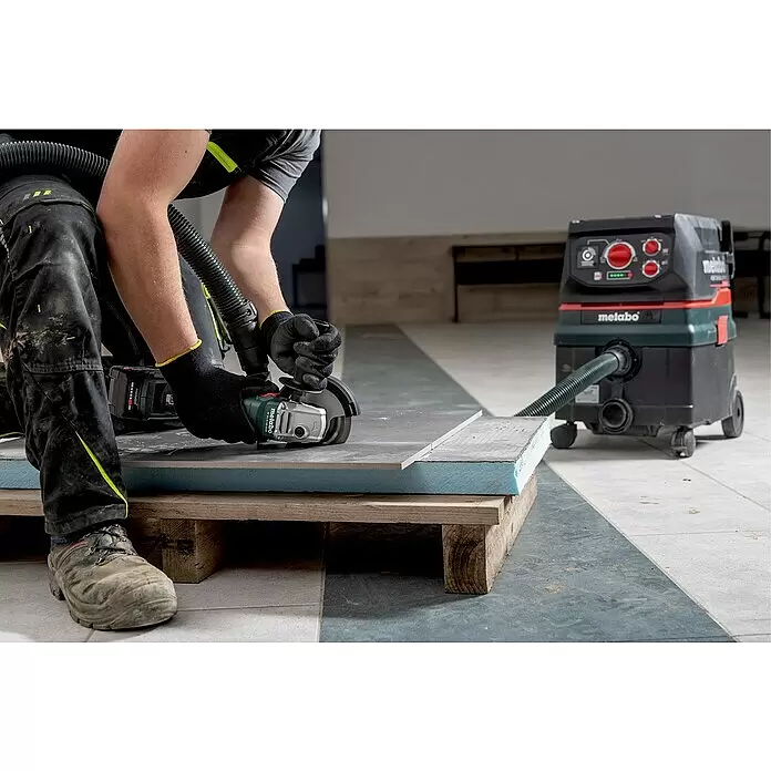 Metabo CAS 18V Akku-Winkelschleifer W 18 L 9-125 - 18 V, Ohne Akku, Durchmesser Scheibe: 125 mm - Ein Arbeiter schneidet eine Fliese mit einem Metabo Winkelschleifer und Staubabsaugung.
