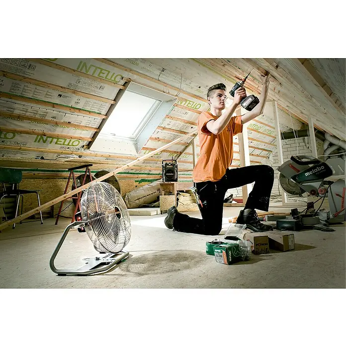 Metabo CAS 18V Akku-Ventilator AV 18 - 18 V, Ohne Akku - Ein junger Handwerker kniet in einem Dachgeschoss und befestigt eine Deckenplatte mit einem Metabo Akku-Bohrschrauber. Im Hintergrund ein Metabo Lautsprecher.