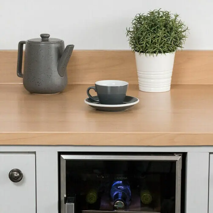 D-c-fix Lámina efecto madera - Haya, 210 x 90 cm, Madera de haya, Autoadhesivo - Primer plano de una encimera con una tetera gris, una taza con plato y una planta en maceta, que muestra una acogedora escena de cocina.