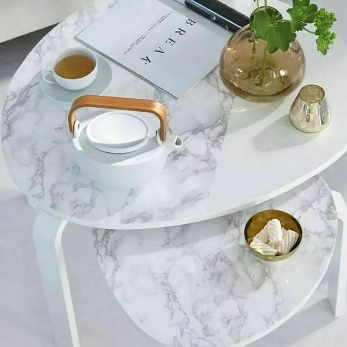 D-c-fix Lámina adhesiva efecto mármol blanco - An x L: 45 x 200 cm - Dos mesas de centro ovaladas con aspecto de mármol. Una tetera, taza, libro, jarrón y vela están en la mesa superior.