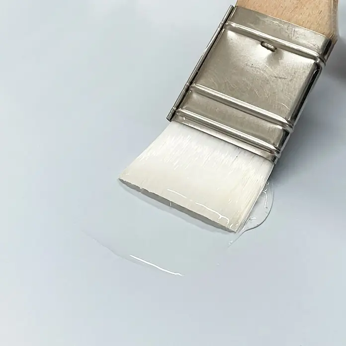 La Pajarita Barniz Supercristal - Incoloro, 50 ml - Primer plano de un pincel aplicando líquido transparente sobre una superficie clara, ideal para proyectos de bricolaje y trabajos detallados.