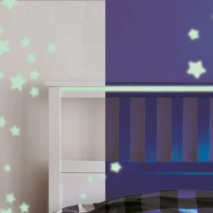 La Pajarita Pintura Fosforescente - Neutro, 75 ml, Brillante - Vista clara y oscura de una mesita de noche con un patrón de estrellas en la pared. La mesa se muestra tanto en blanco como en azul oscuro.