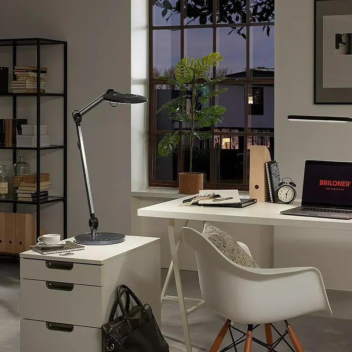 Brilo LED-Tischleuchte Office - 7 W, Ø x H: 20 x 74 cm, Anthrazit, Warmweiß - Schreibtischleuchte im modernen Arbeitszimmer. Die Leuchte ist schwarz und silber und steht auf einem weißen Nachttisch.