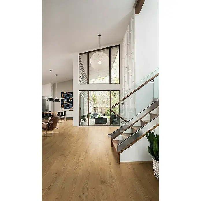 LOGOCLIC Aquaprotect Laminado Roble Sherwood - 1.285 x 192 x 12 mm, Roble, AC5, Resistente al agua - Interior luminoso y moderno con pisos de madera, grandes ventanales y una escalera con barandilla de vidrio. Espacio abierto.