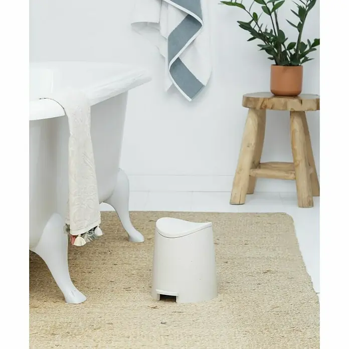 Tatay Standard Cubo con pedal - 3 l, Plástico, Beige - El cubo de basura blanco de plástico está sobre una alfombra beige frente a una bañera blanca y un taburete de madera con una planta.
