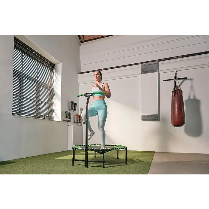 Salta Trampolin Fitness - Durchmesser: 140 cm, Grün - Frau benutzt Salta Fitness Trampolin mit Haltegriff. Ideal für ein effektives und gelenkschonendes Training zu Hause.
