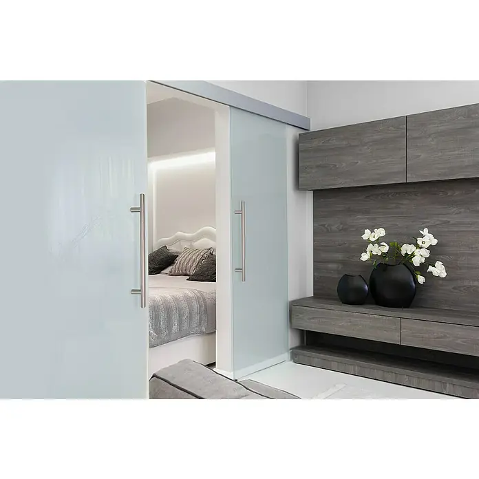 Siro Möbelgriff - Typ Möbelgriff: Stange, Sonstige, Sonstige, Länge: 550 mm - Blick durch eine Glasschiebetür in ein Schlafzimmer mit weißen Wänden und grauen Möbeln. Ein stilvolles Design für modernes Wohnen.