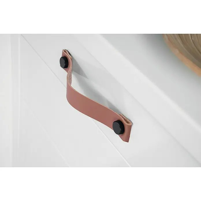 Siro MöbelgriffTyp Möbelgriff: Sonstige, Leder, Sonstige, Braun/Schwarz - Nahaufnahme eines weißen Schranks mit einem Ledergriff in Rosatönen, der mit schwarzen Schrauben befestigt ist.