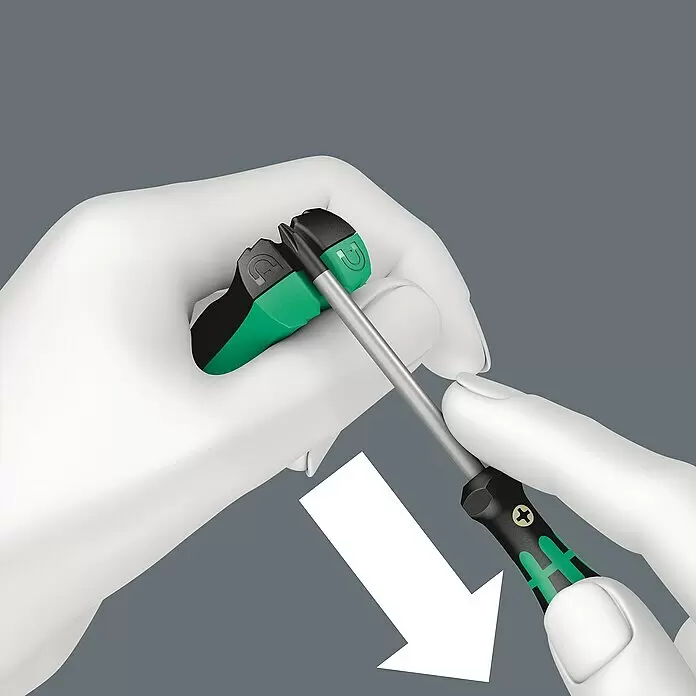 Wera Magnetisiergerät 9500 - Geeignet für: Schraubendreher - Eine weiß behandschuhte Hand steckt einen schwarz-grünen Schraubendreher-Bit in einen passenden Magnetisierer, durch einen Pfeil angezeigt.