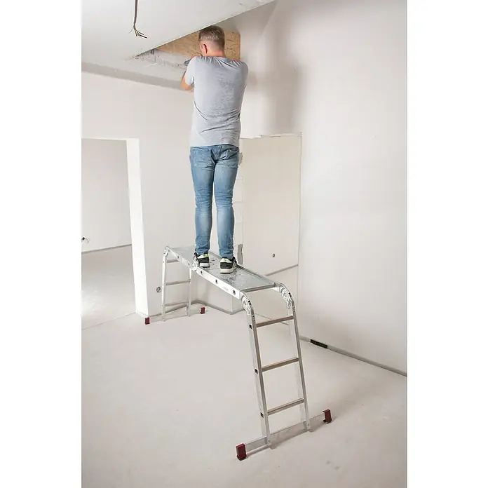 Krause Corda Gelenkleiter-Plattform - Passend für: Krause Corda Sprossen-Gelenkleiter, 1 Stk. - Ein Mann steht auf einer Aluminium-Mehrzweckleiter und arbeitet an der Decke in einem hellen Raum. Die Leiter ist vielseitig einsetzbar.