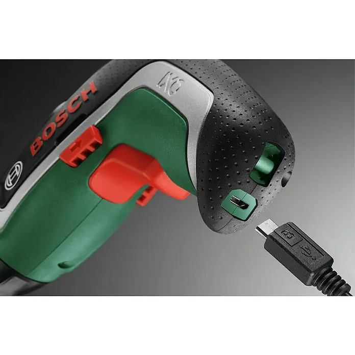 Bosch Atornillador de batería IXO 7 - 3,6 V, 1 batería, 2 Ah, 5,5 Nm, Juego de brocas y accesorios - Primer plano de un atornillador inalámbrico Bosch que se está cargando con un cable USB. La herramienta es verde, negra y plateada.