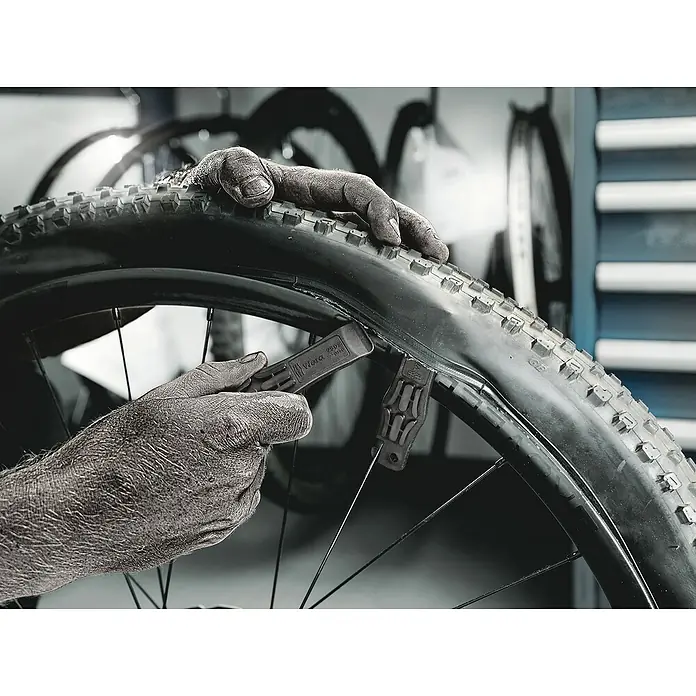 Wera Werkzeug-Set Bicycle Set 1 - 12 -tlg. - Fahrradreparatur: Nahaufnahme eines Reifens, der mit einem Reifenheber von der Felge genommen wird, Werkzeug und Reifen im Fokus.