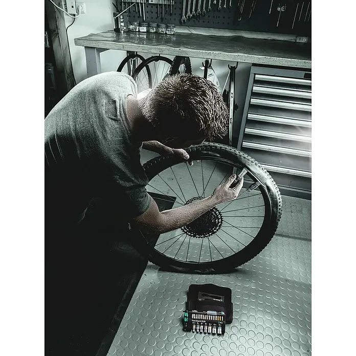 Wera Werkzeug-Set Bicycle Set 3 - 40 -tlg. - Ein Mann repariert ein Fahrradrad mit Werkzeugen von Wera Tool-Check PLUS. Perfekt für Reparaturen und Wartung.