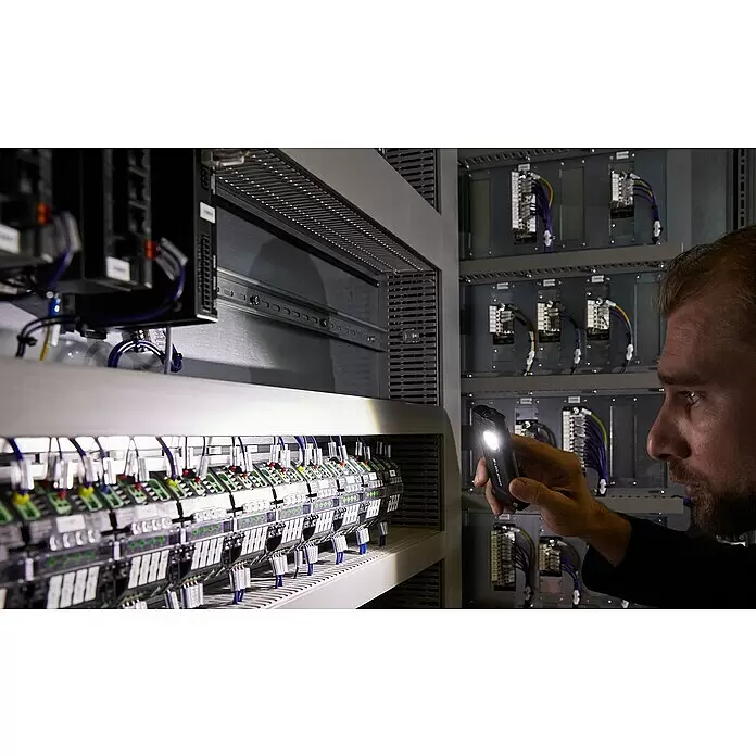 Ledlenser LED-Arbeitsleuchte iF2R - 200 lm, IP54 - Schwarze Ledlenser Taschenlampe wird von einer Person zur Beleuchtung eines Schaltschranks gehalten.