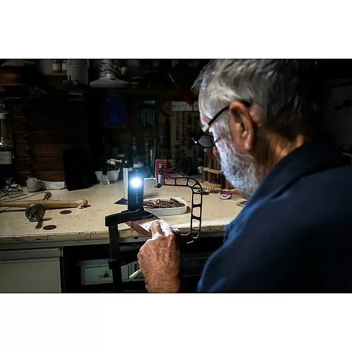 Ledlenser LED-Arbeitsleuchte iF2R - 200 lm, IP54 - Schwarze rechteckige Taschenlampe beleuchtet ein Werkstück auf einer Werkbank, mit einer Klammer befestigt.