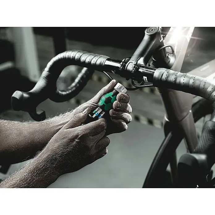 Wera Mini-Schraubendreher-Set Bicycle 5 - 7 -tlg. - Nahaufnahme eines Werkzeugs mit austauschbaren Bits, das an einem Fahrradlenker gehalten wird. Ideal für Reparaturen und Anpassungen unterwegs.