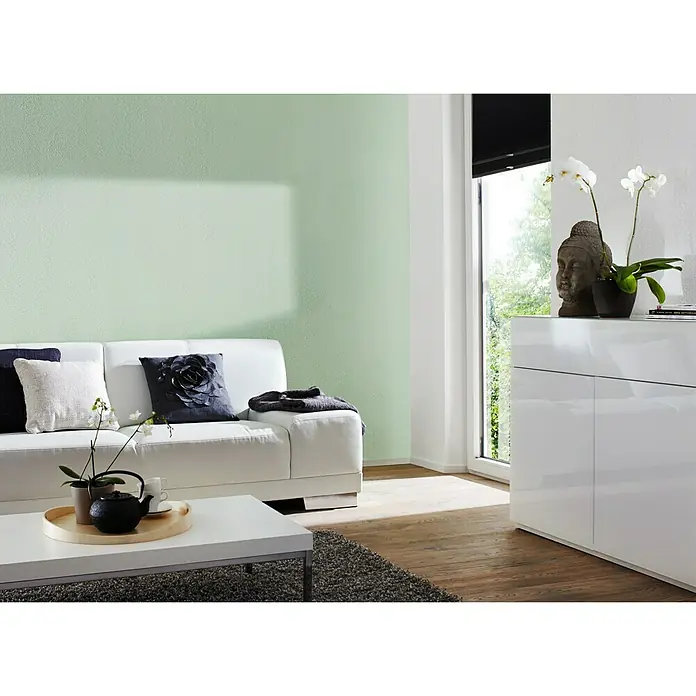 Knauf Putz-Abtönfarbe Compact Color - Jade, 2 g - Wohnzimmer mit weißem Sofa, Couchtisch und einer Kommode dekoriert mit einer Buddha-Statue und Orchideen.
