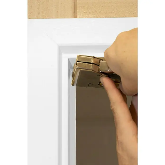Primo Universaldichtung Densa 25 - Weiß, 6 m, Passend für: Fenster, Türen, Möbel mit Spaltenbreite 2 – 5 mm - Eine Person befestigt mit einem goldenen Tacker ein Türschloss an einem weißen Türrahmen. Werkzeug und Hand stehen im Fokus.