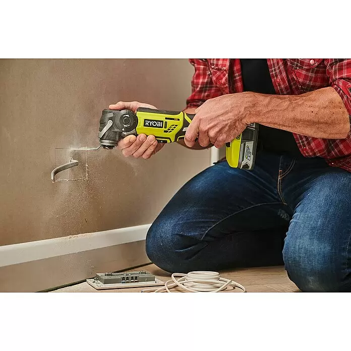 Ryobi ONE+ Maschinenpaket - Akku-Multifunktionswerkzeug R18MT-0 + gratis Starter-Kit - Person schneidet mit einem gelb-schwarzen Ryobi Multifunktionswerkzeug eine Öffnung in eine Wand und erzeugt dabei Staub.