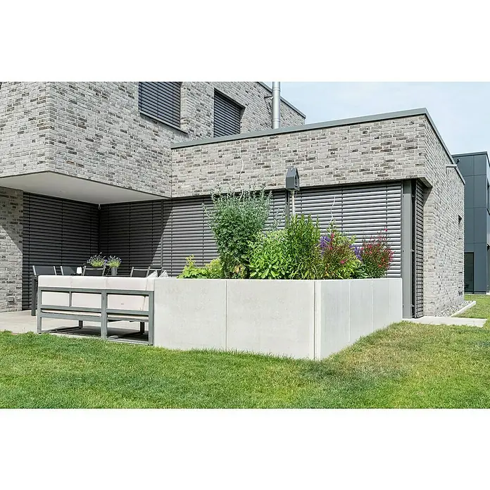 Diephaus L-Stein InneneckeBewehrt, Höhe: 155 cm, Breite: 100 cm, Stärke: 12 cm, Grau - Außenaufnahme eines erhöhten Pflanzgefäßes aus Beton mit üppigem Grün und bunten Blumen, das eine moderne Gartengestaltung zeigt.
