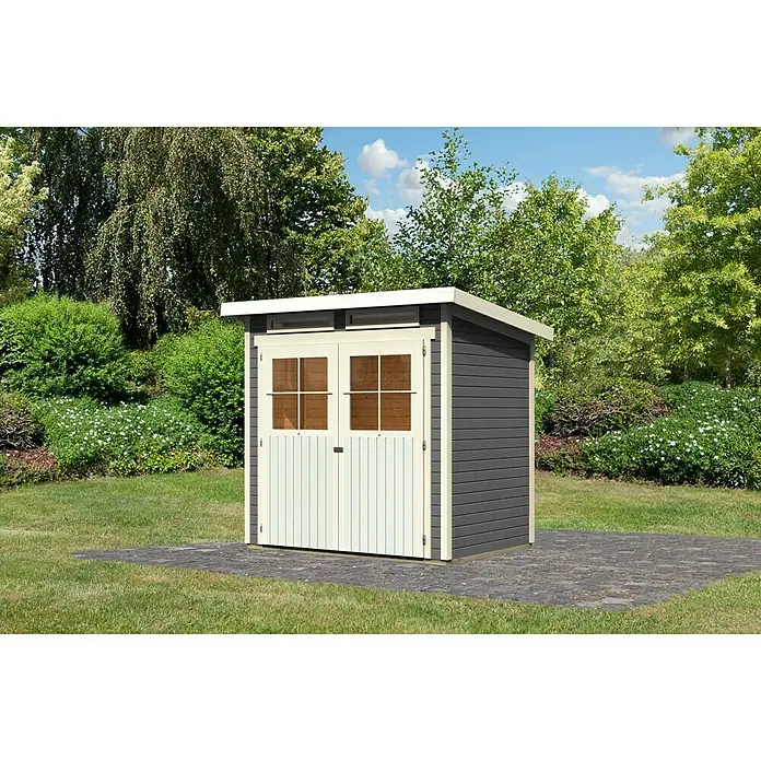 Karibu Gartenhaus Glücksburg - Außenmaß inkl. Dachüberstand (B x T): 242 x 175 cm, Holz, Terragrau, Grundfläche: 3,02 m² - Ein graues Gartenhaus mit weißen Türen und Fensterrahmen auf einem Steinpflaster im Grünen.