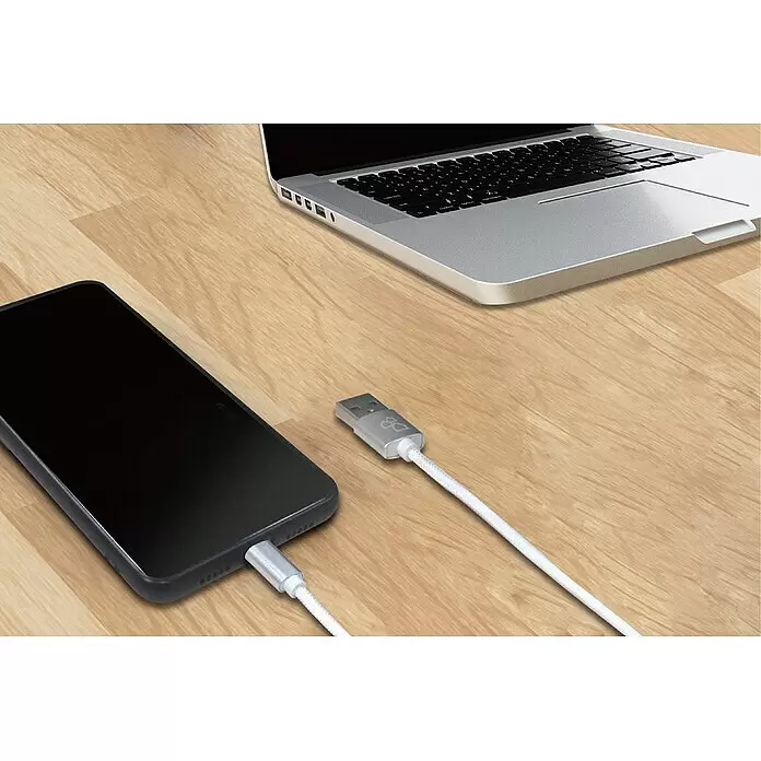 BAUHAUS USB-Kabel - 3 m, USB A-Stecker - Schwarzes Smartphone mit weißem geflochtenen Ladekabel und silbernem USB-Stecker auf Holz, neben einem silbernen Laptop.