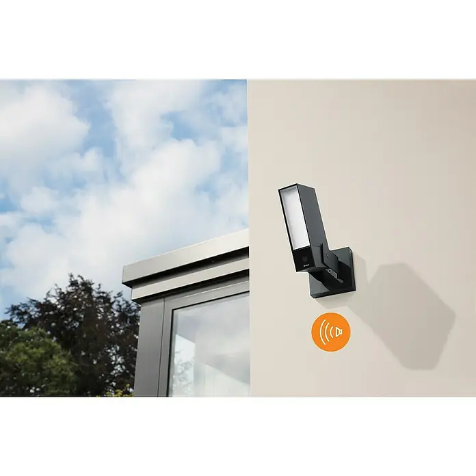 Netatmo Cámara de vigilancia con sirena - Negro, Ángulo de detección: 100 °, Alcance de detección: 15 m - Primer plano de una cámara de seguridad Arlo con luz integrada, montada en una pared de color claro.