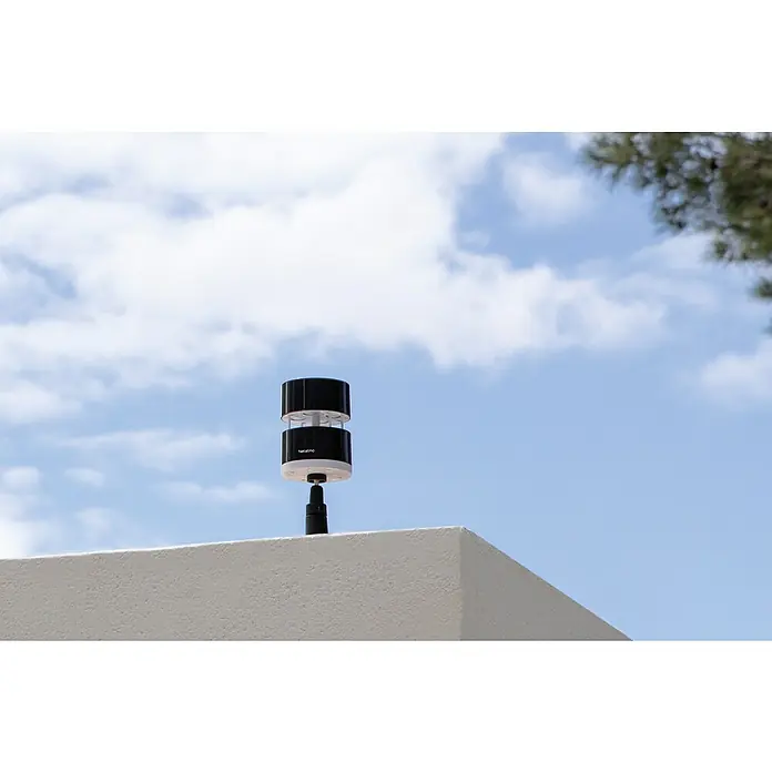 Netatmo Anemómetro - Funciona con pilas, Diámetro: 8,5 cm, Negro - Estación meteorológica Netatmo montada en un techo contra un cielo azul. Diseño cilíndrico compacto para mediciones ambientales precisas.