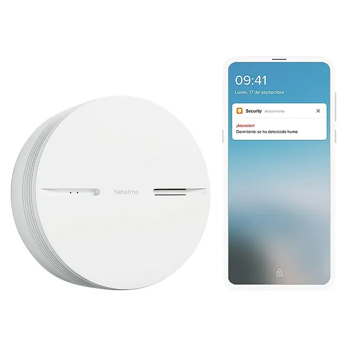 Netatmo Detector de humo inteligente - Diámetro: 11,5 cm, Duración de batería: 10 años, Señal de alarma: 85 dB - Un detector de humo inteligente Netatmo junto a un smartphone que muestra una alerta de humo.