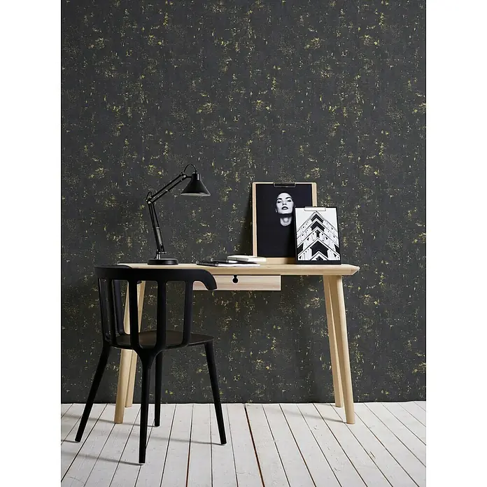 A.S. Création Trendwall Vliestapete - Schwarz/Gold, Betonoptik, 10,05 x 0,53 m - Der elegante Arbeitsbereich mit einem minimalistischen Schreibtisch und einem stilvollen schwarzen Stuhl. Eine moderne Tischlampe beleuchtet die Arbeitsfläche.
