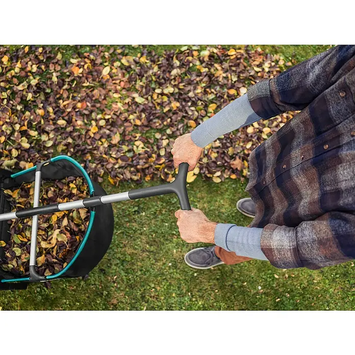 Gardena Laubsammler - 73 x 40 x 45 cm - Eine Person benutzt einen Laubsammler, um Herbstlaub vom Rasen zu entfernen, mit Fokus auf die Gartenarbeit.