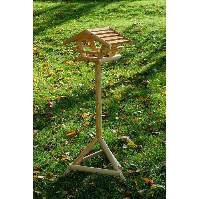 Dobar Vogelhaus Bernie Bernstein - 44 x 44 x 101 cm, Holz, Braun - Detailaufnahme eines hölzernen Vogelhauses auf einem Ständer inmitten eines Rasens voller Herbstlaub. Die Konstruktion ist stabil und naturnah.